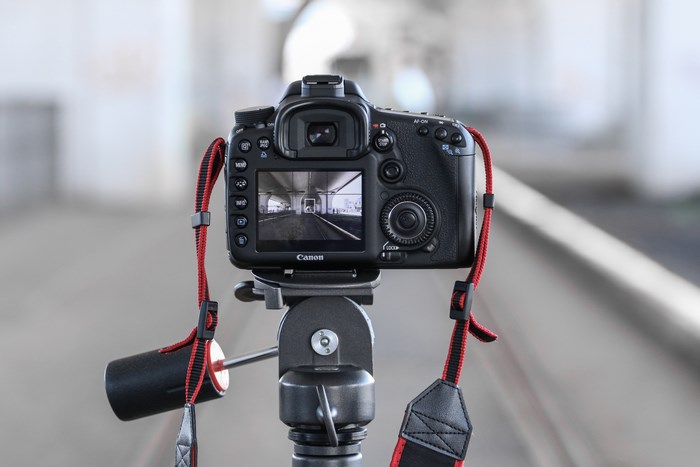 Canon DSLR camera on a tripod with a red strap