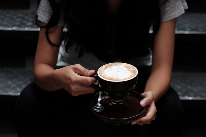 Person Holding Cup of Latte on Steps