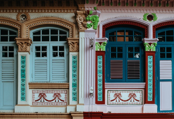 Ornate pastel colored building facade with windows and shutters