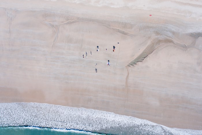 Aerial view of people on a sandy beach with waves