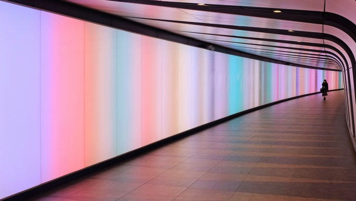 Person walking through illuminated tunnel at King's Cross