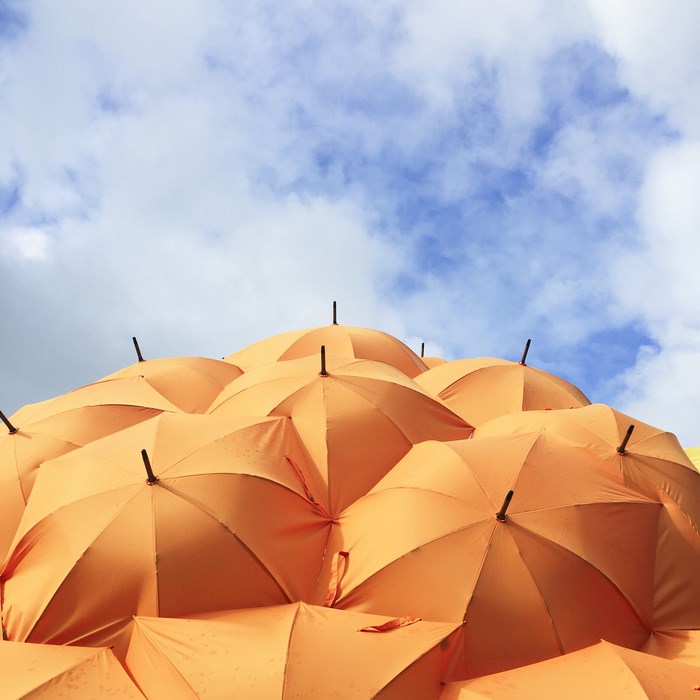 Orange umbrellas against a blue sky with clouds