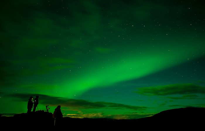 People photographing the Northern Lights in a starry sky