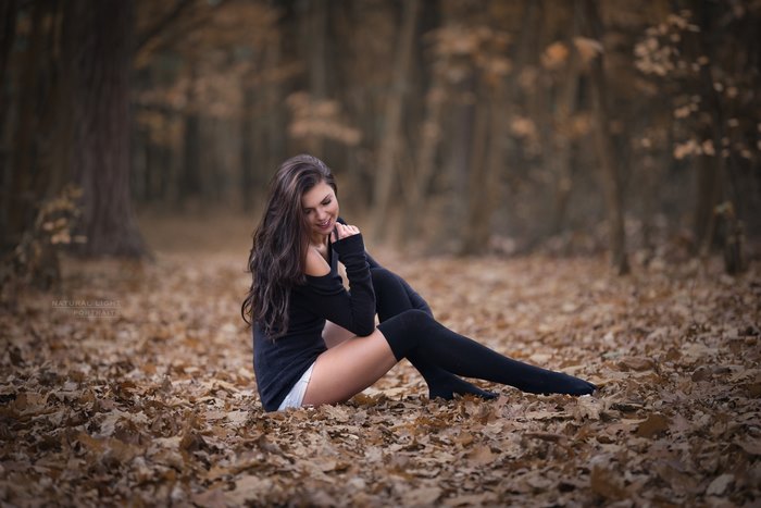 Woman with long hair sitting in autumn leaves