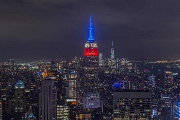 Empire State Building illuminated in red and blue at night, New York City skyline
