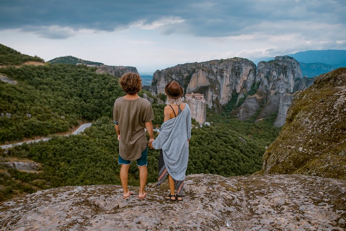 Couple holding hands overlooking Meteora rock formations
