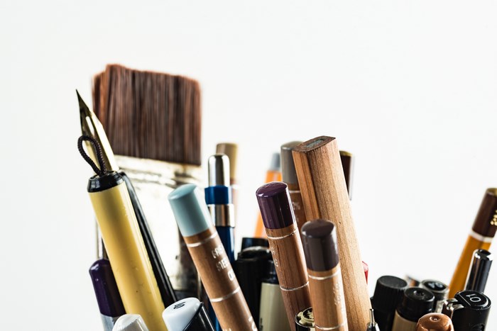Close-up of art supplies including pens, pencils, and a paintbrush