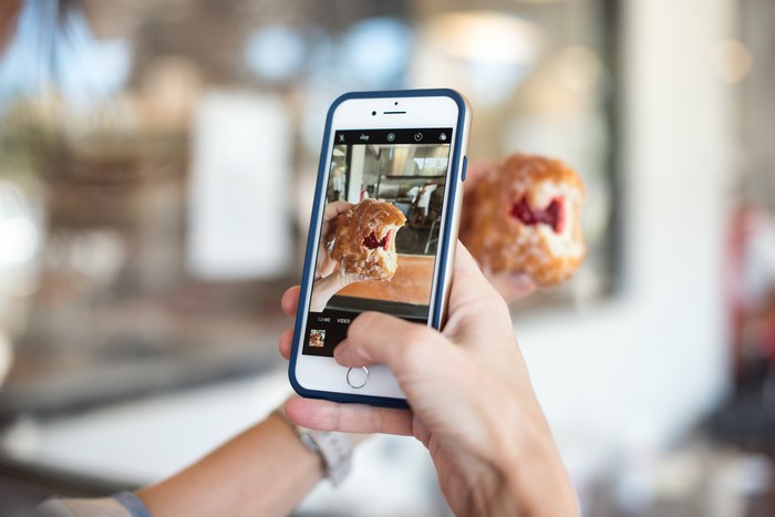 Person taking a photo of a donut with an iPhone