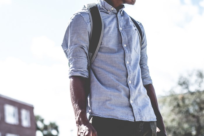 Man with backpack wearing a blue button-up shirt