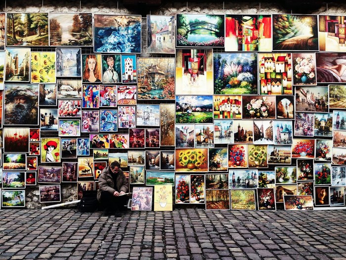 Street Artist Selling Colorful Paintings on Cobblestone