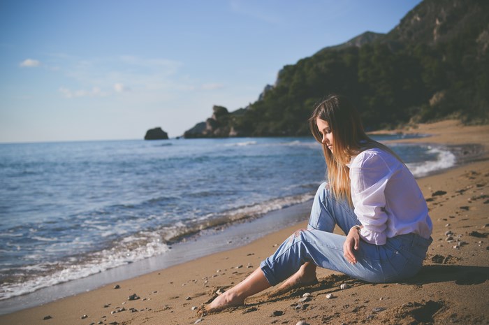 Woman sitting on a sandy beach by the ocean