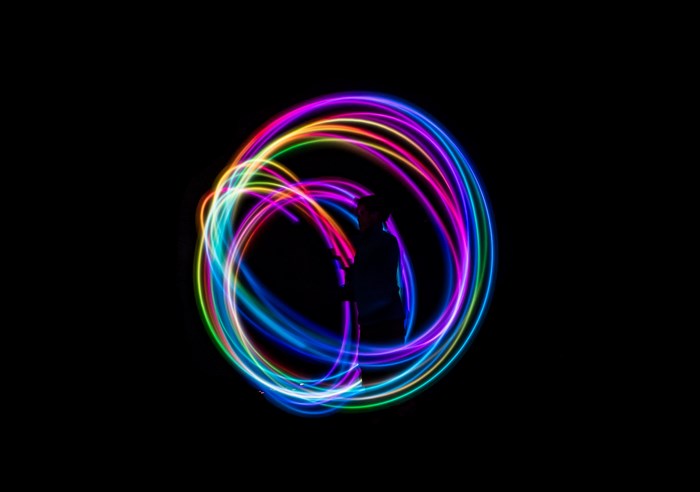Person silhouetted within a rainbow light trail