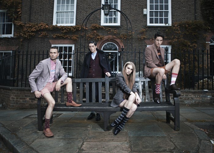 Four people posing on a bench in front of a building