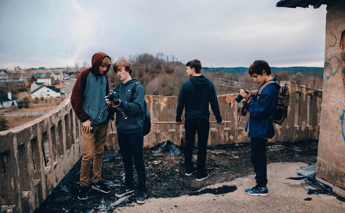 Four young men with cameras on a burnt rooftop