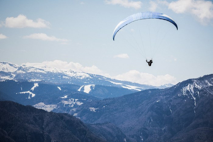 Paraglider flying over snow-capped mountains