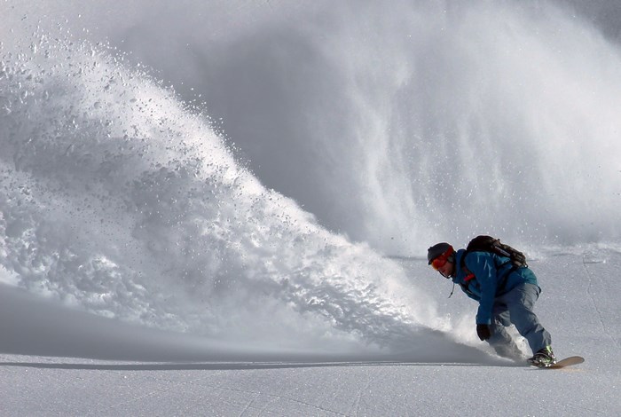 Snowboarder spraying snow while riding down a mountain