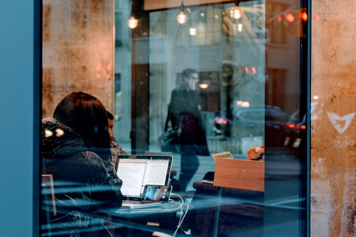 Woman working on a MacBook in a cafe with reflections