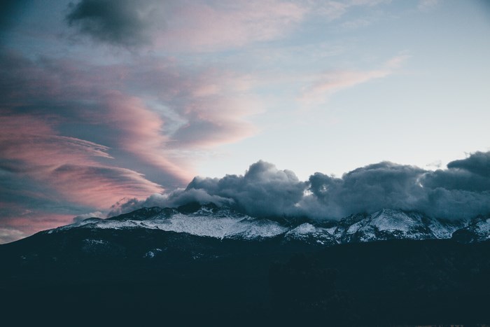 Snow-capped Longs Peak mountain under a colorful sunset sky