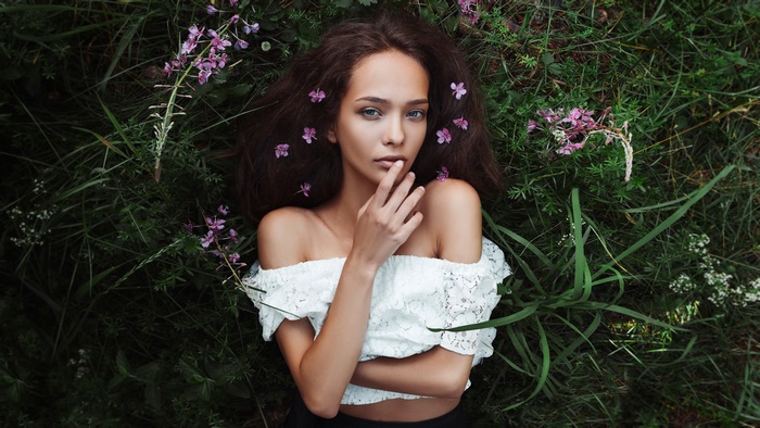 Woman with flowers in her hair lying in grass