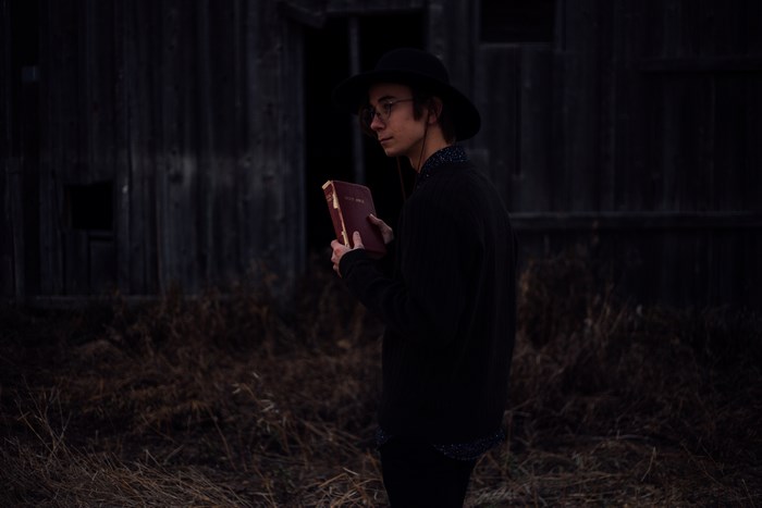 Man in hat holding a bible outdoors