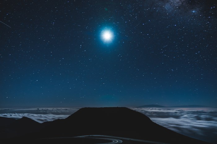 Night sky over clouds with a bright moon and stars