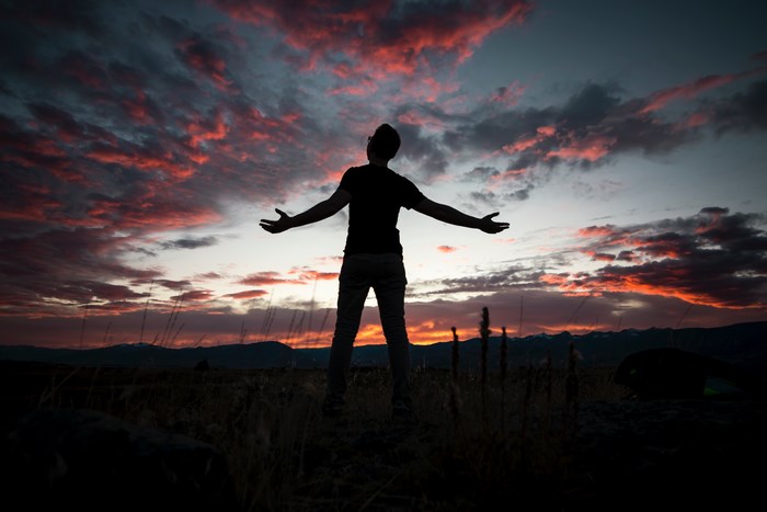 Silhouette of a man with arms outstretched at sunset in Montana