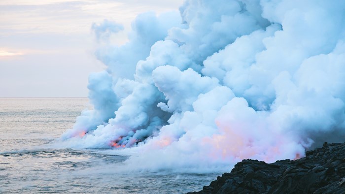 Lava flowing into the ocean with steam and smoke