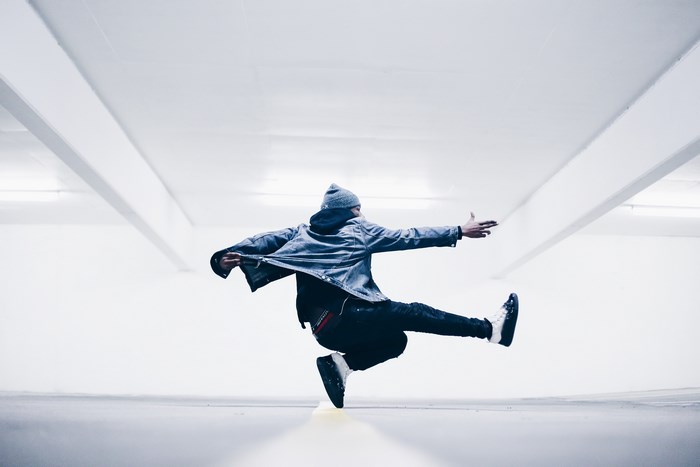 Breakdancer in motion in a white parking lot