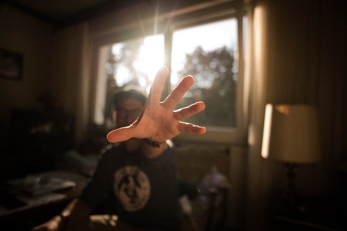 Man reaching out with hand in front of window