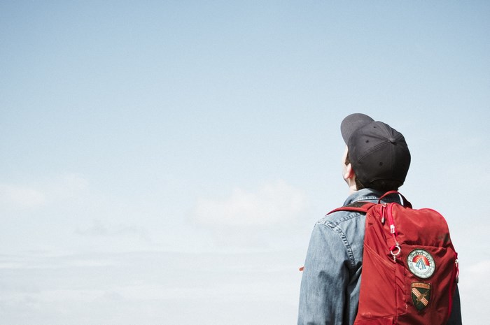 Man in Jean Jacket with Red Backpack and Baseball Hat