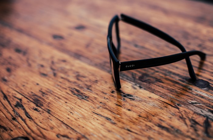 Black Gucci glasses on a wooden table