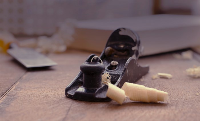 Wood plane with shavings and chisel on a wooden surface