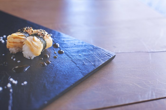 Tamagoyaki sushi with sesame seeds on a slate plate