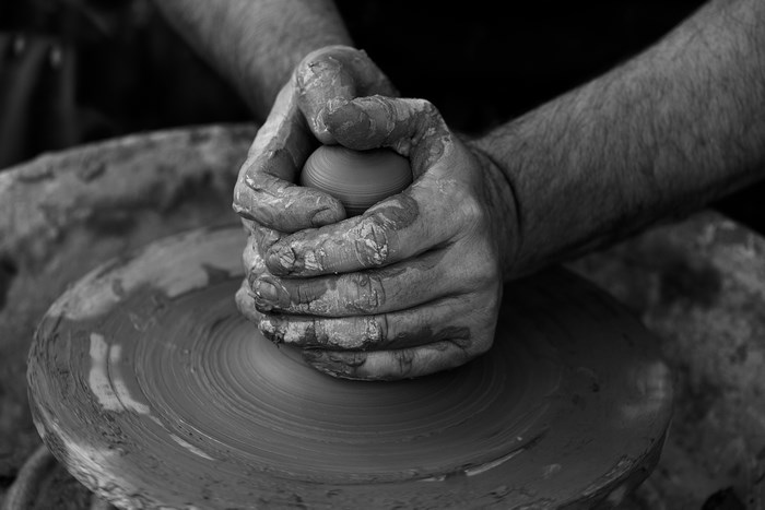 Potter's hands shaping clay on a pottery wheel
