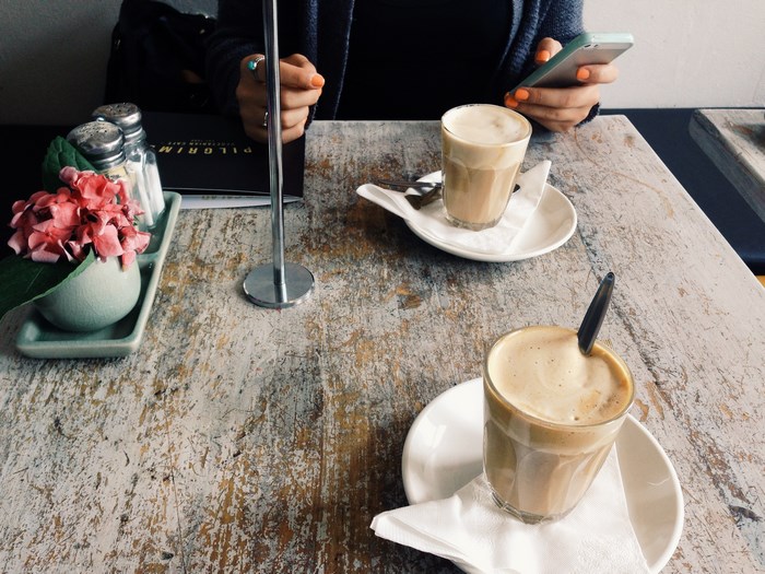 Person using a smartphone at a table with coffee