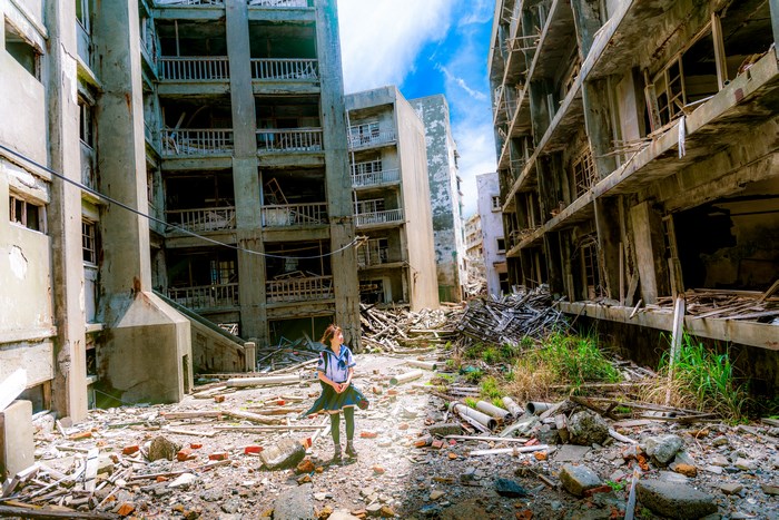 Young girl in a ruined city with rubble and destroyed buildings