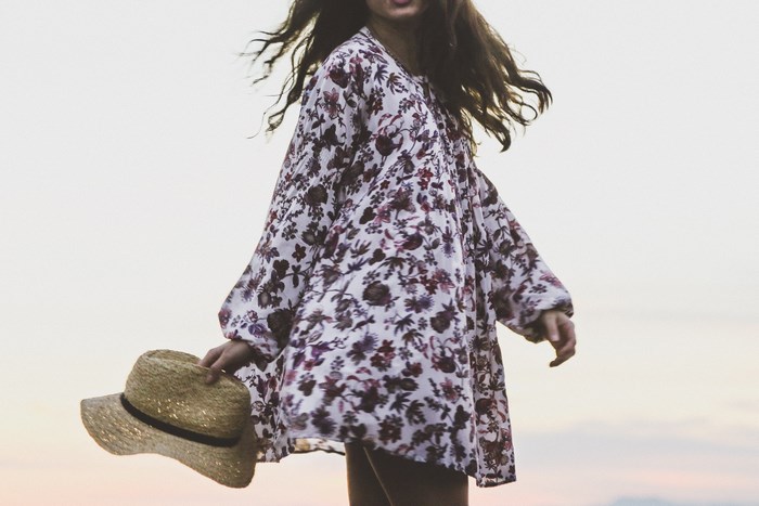 Woman in floral dress holding a straw hat