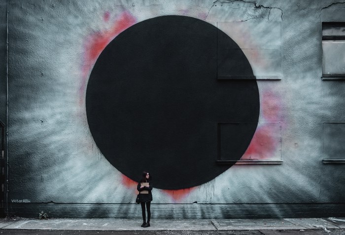 Girl in front of a large eclipse mural in Berlin