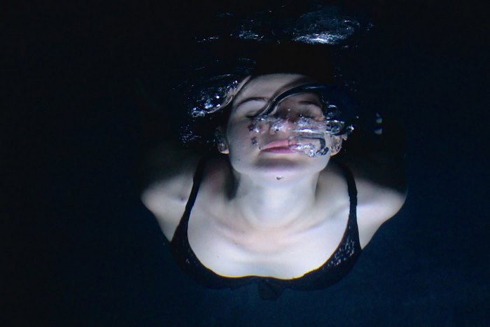 Woman exhaling bubbles underwater