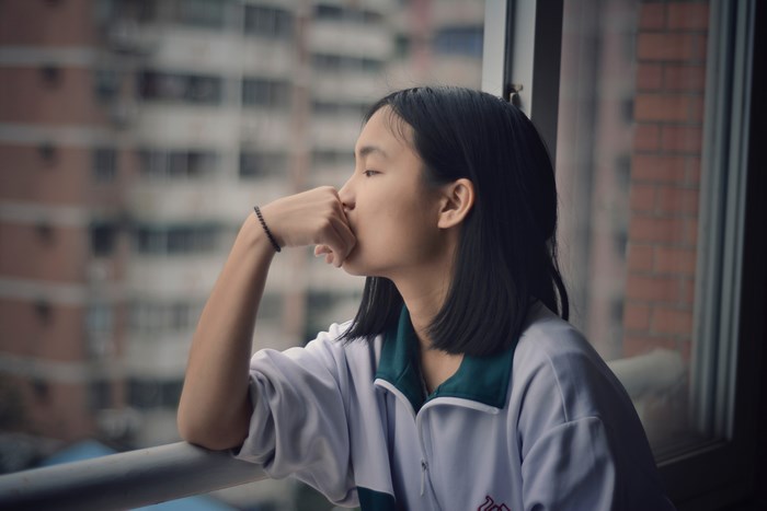 Girl looking out a window in a city