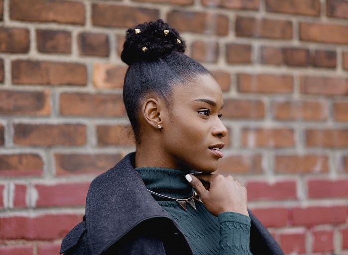 Woman with a bun hairstyle in front of a brick wall