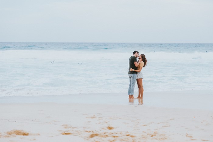 Couple kissing on the beach with waves
