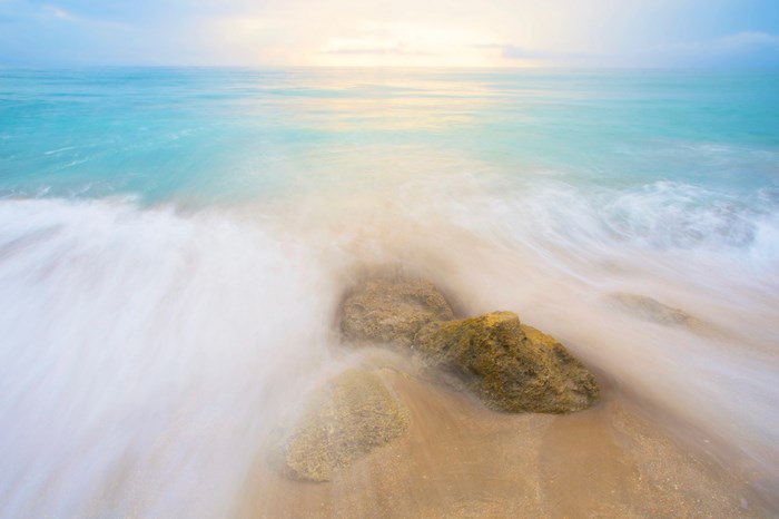 Long exposure of waves crashing on rocks at dawn