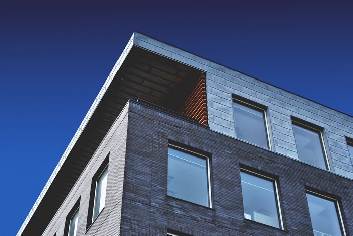 Modern building with dark brick and metal facade under clear sky
