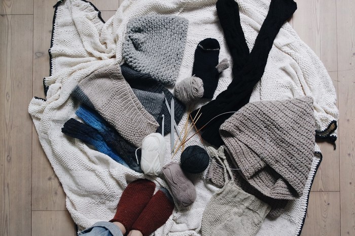 Knitting supplies and finished knitwear laid out on a blanket