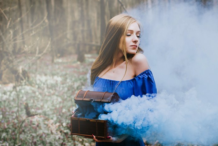 Woman in blue dress holding a treasure chest with smoke