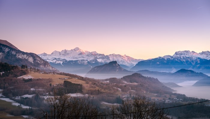 Misty mountain range at sunrise with purple sky