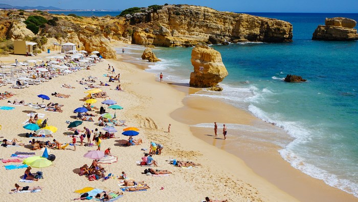 People relaxing on a sunny beach in Portugal with cliffs