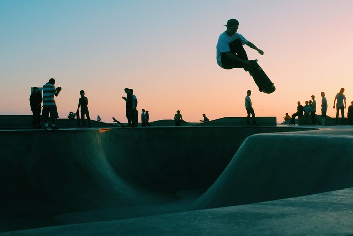 Skateboarder jumps at Venice Skate Park during sunset