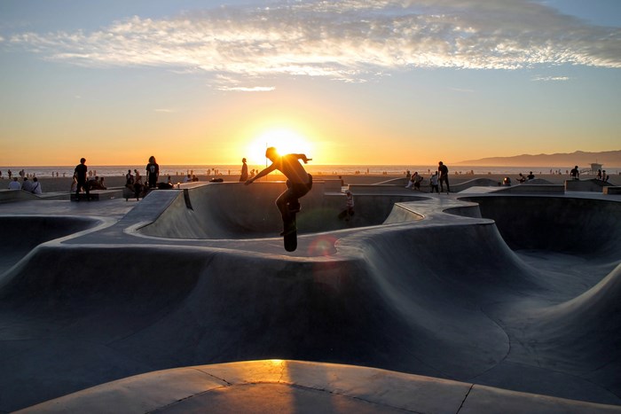 Skateboarder jumps at Venice Beach Skatepark during sunset